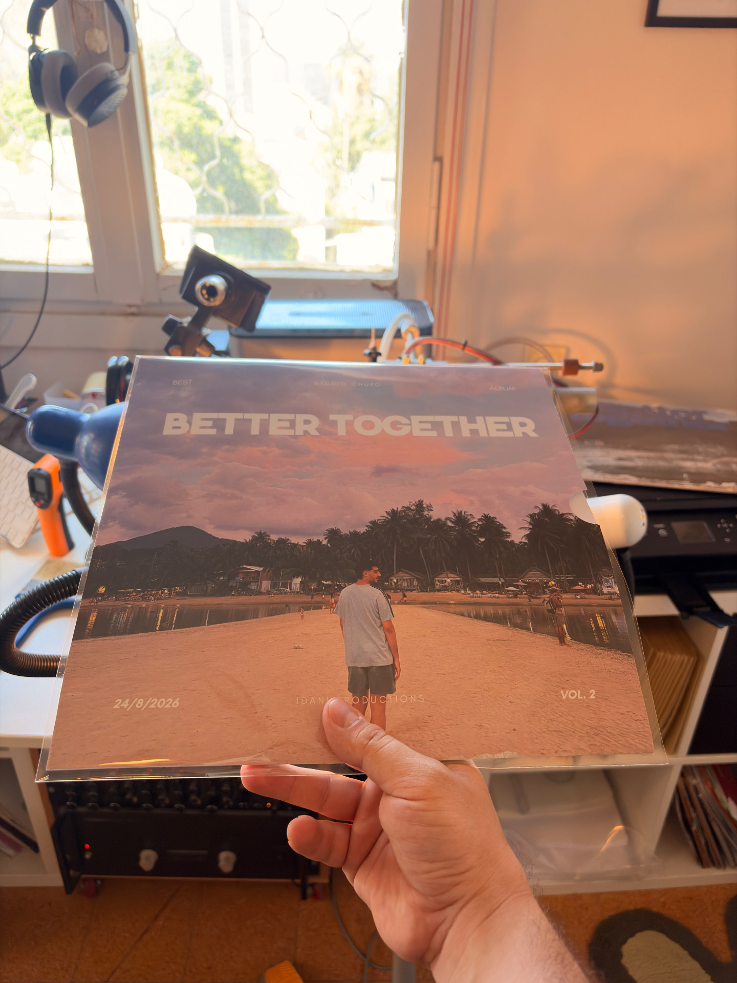 עטיפת תקליט אישי BETTER TOGETHER Vol. 2 מוחזקת ביד לצד מכונת החריטה בסטודיו PLASTIK